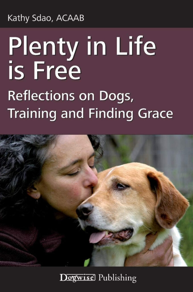 Book cover of "Plenty in Life is Free" by Kathy Sdao with a photo of a woman kissing a tan dog on the cheek